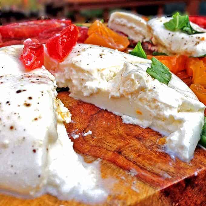 A close up burrata cheese on board with garnigh