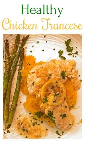 Chicken atop spaghetti squash next to asparagus spears on plate