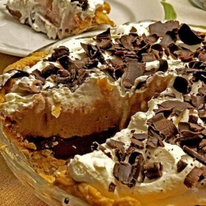 Baked pie with chocolate cream, plate slice behind on table