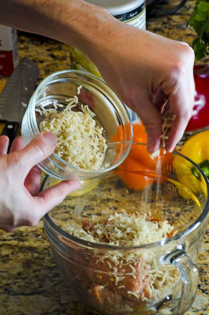 Adding brown rice to a mixing bowl for a sausage and peppers recipe.