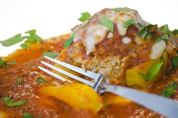 A plate of food with a fork, with Stuffed peppers and Italian sausage