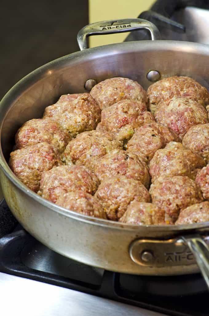 Searing the bottoms of mozzarella stufffed meatballs on the stove top.
