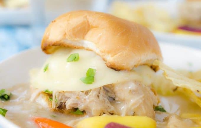 A close up side view hot turkey sandwich in bun, vegetable in foreground