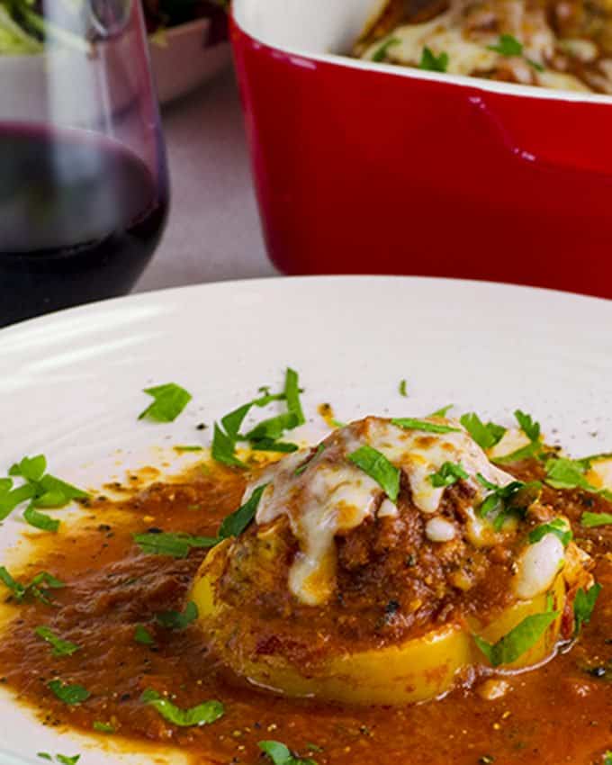 Plate of baked stuffed peppers garnished with chopped Italian parsley.