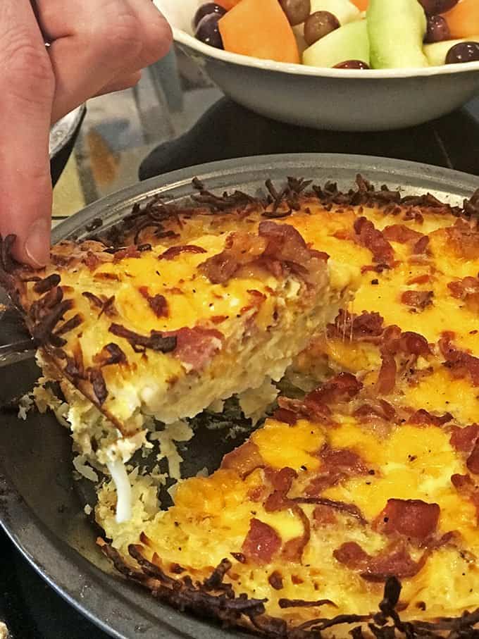 Someone removing slice of quiche from pan