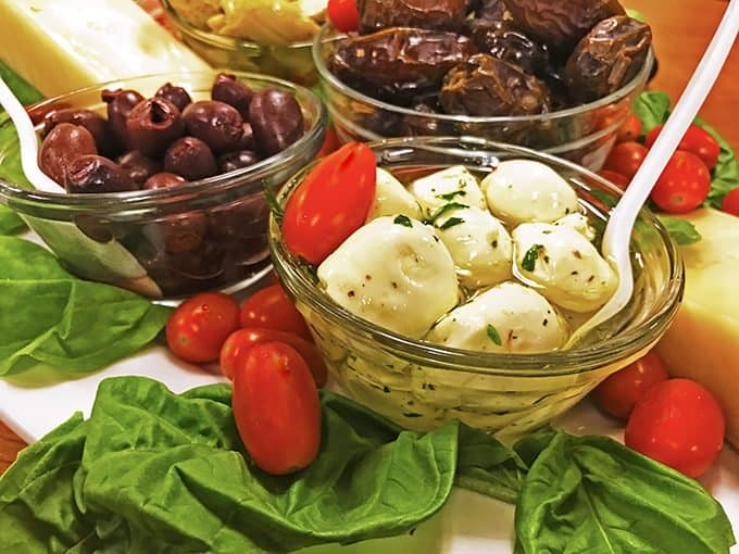 A bowl of cheese with olives and tomatoes