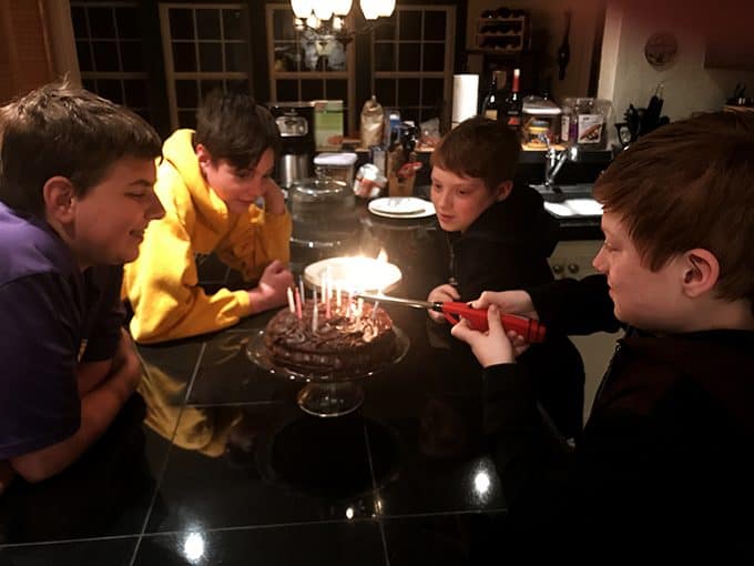 Boys lighting candles on a cake