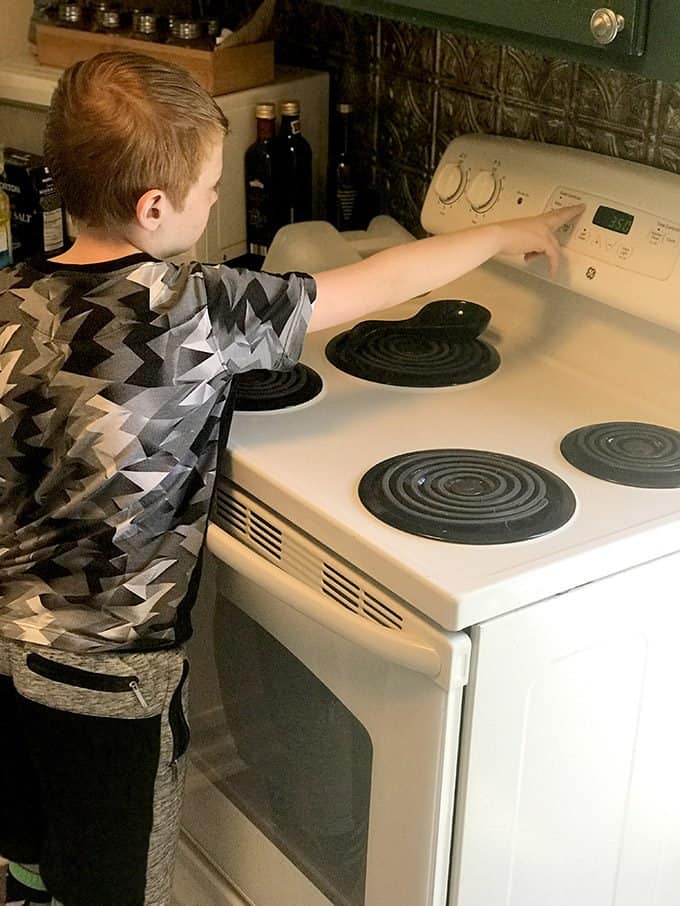 A stovetop oven sitting inside of a kitchen with a boy