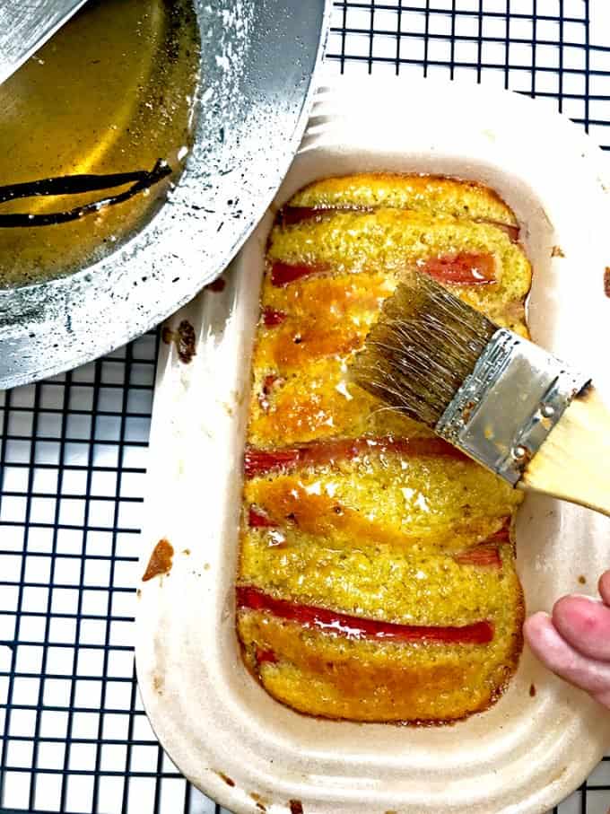 Someone glazing simple syrup on baked loaf using pastry brush