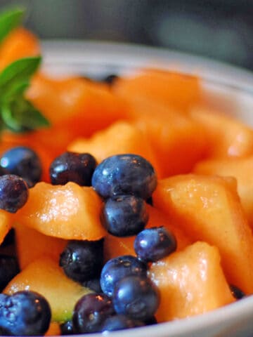 A bowl of blueberries and choped cantaloupe.
