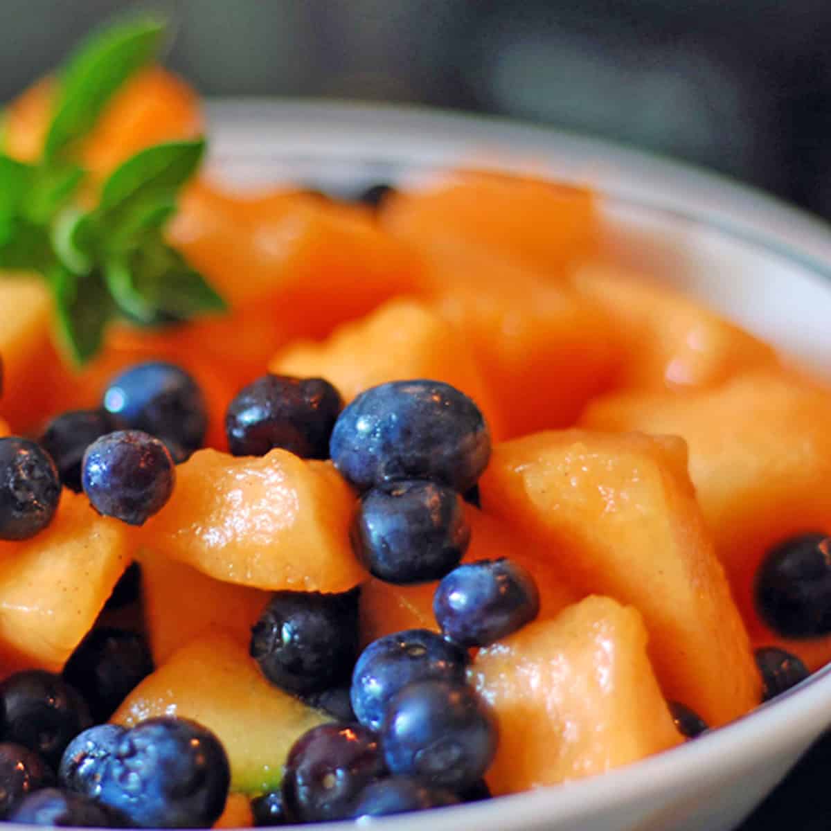 A bowl of blueberries and choped cantaloupe.