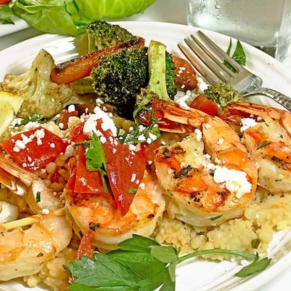 A plate of griled shrimp over couscous.