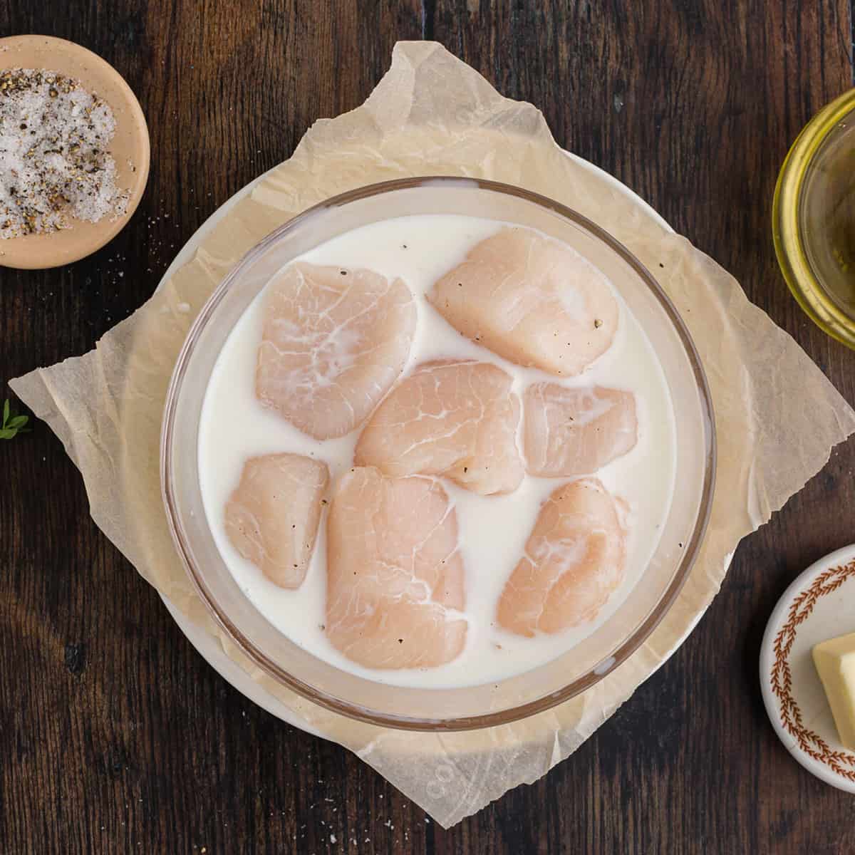 A bowl of scallops being soaked in milk.