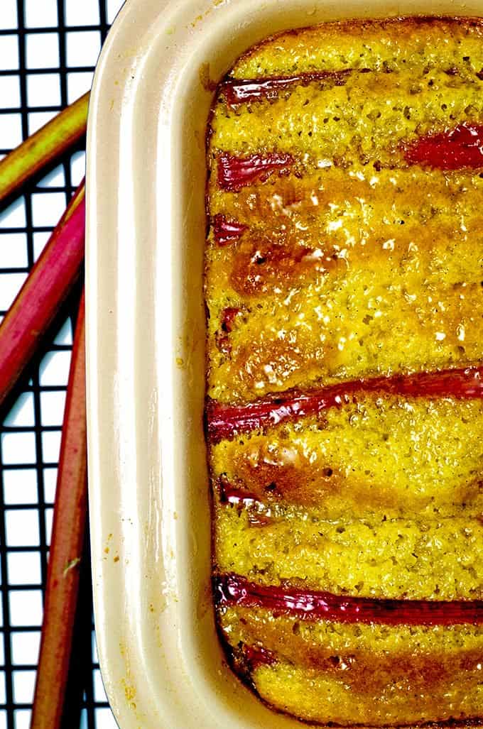 Cllose up baked vanilla rhubarb pound cake on cooling rack with rhubarb stalks 