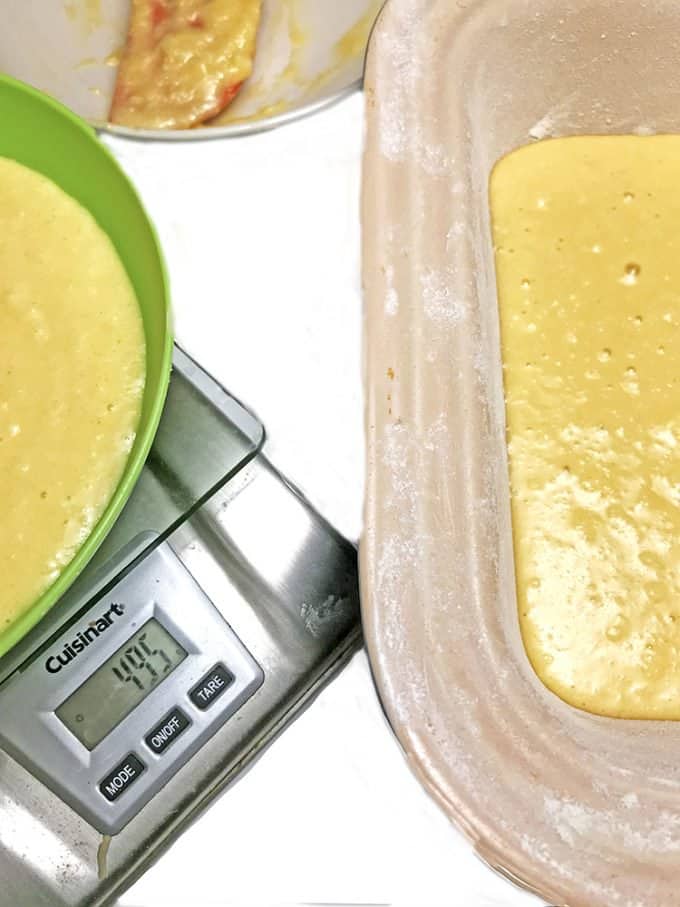 Batter in bowl being weighed next to filled loaf pan