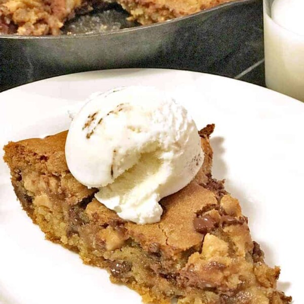 Wedge of chocolate chip cookie pie with scoop of ice cream on plate