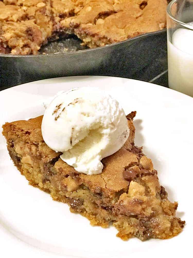 Wedge of chocolate chip cookie pie with scoop of ice cream on plate
