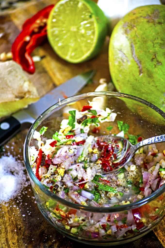 Chopped vegetable in bowl with spoon near cutting board, knife and kosher salt