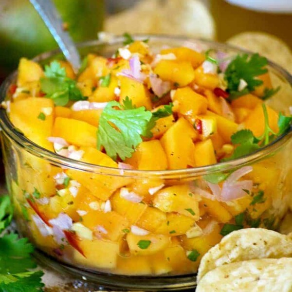 A glass bowl of papaya salsa serving spoon cilantro