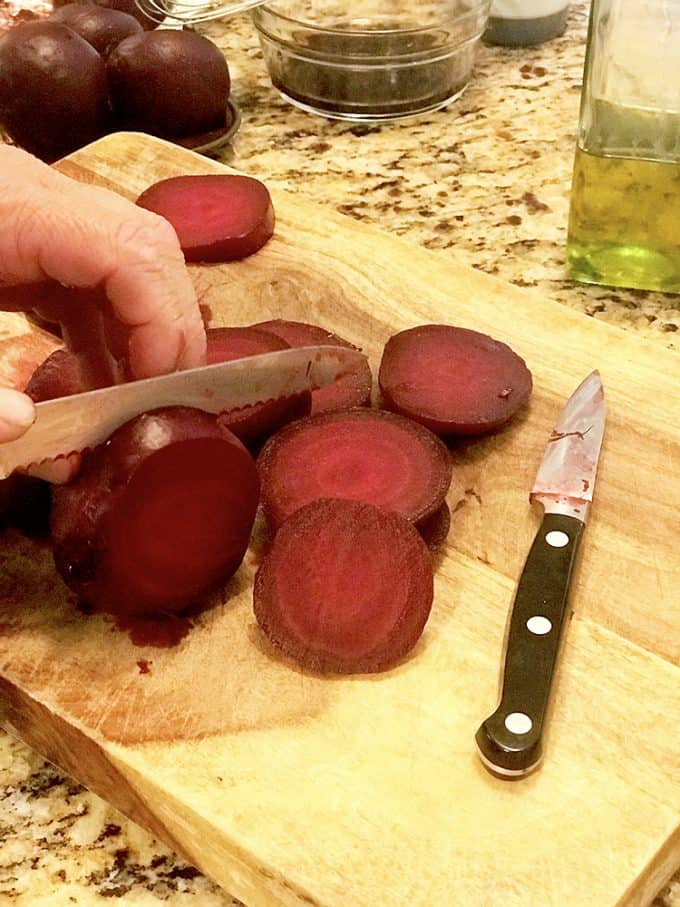 Someone slicing roasted beets one board