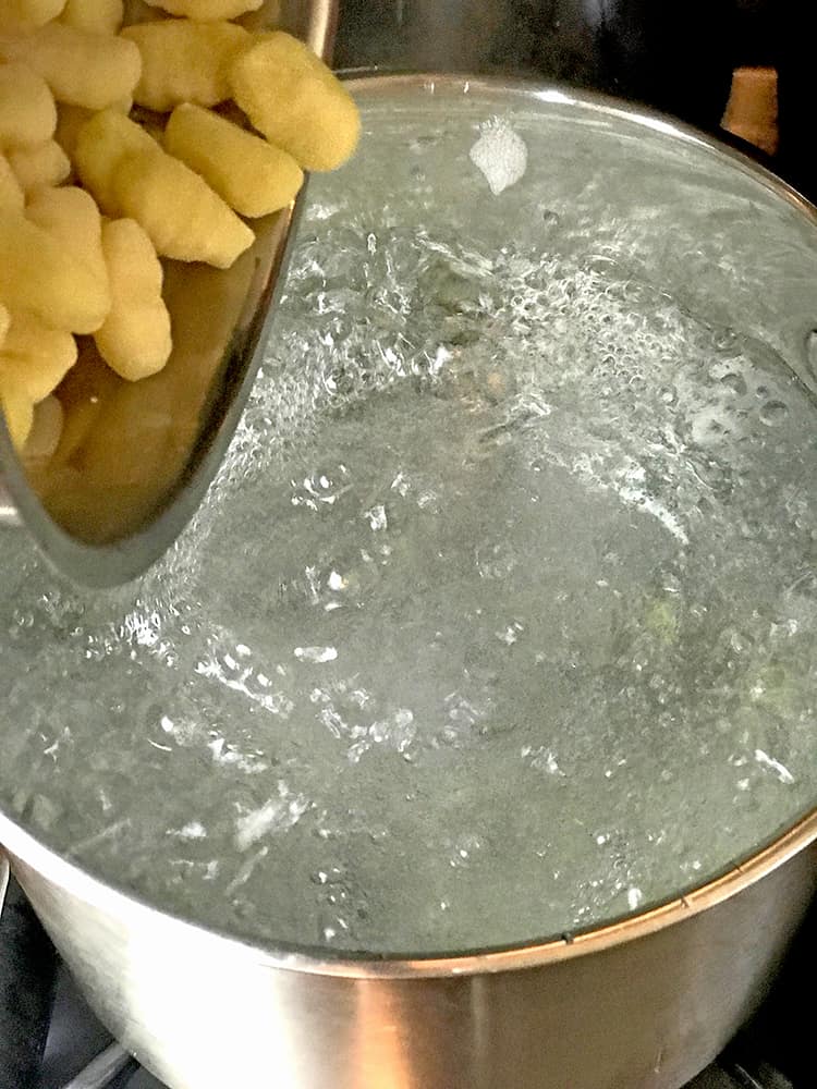 A pot of boiling water with raw pumpkin gnocchi about to go in