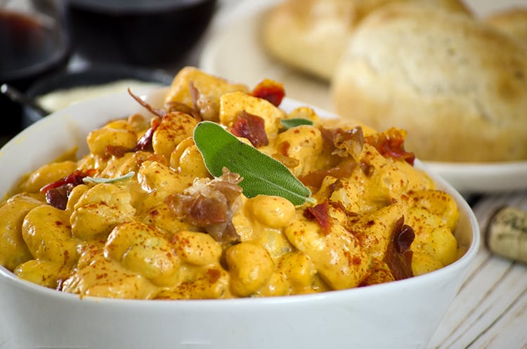 Close up Pumpkin gnocchi with herbs in serving bowl, bread in background