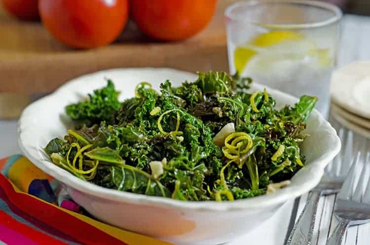 Antique dinner bowl containing steamed kale on a table.