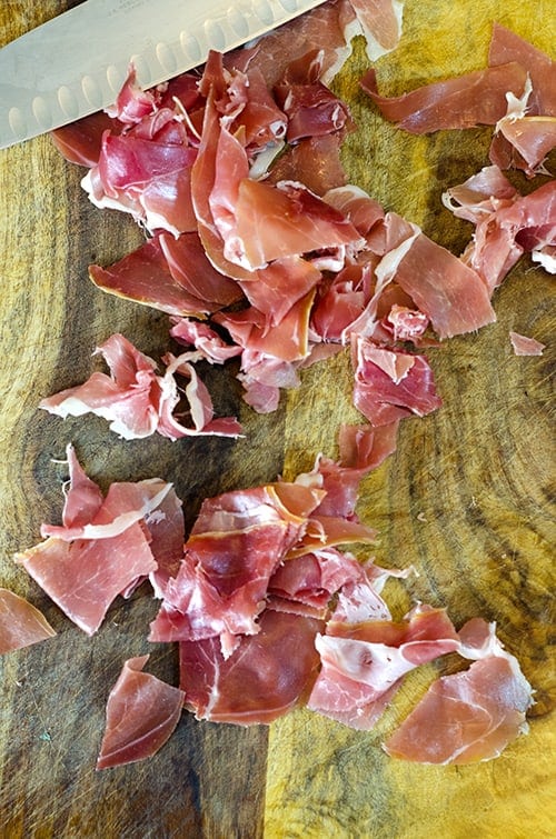 Prosciutto is sliced before crisping it up in a hot skillet.