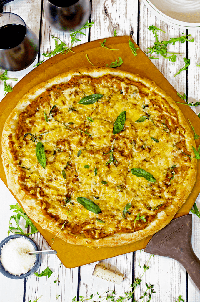 Pizza topped with fresh herbs, sitting on top of a wooden peel