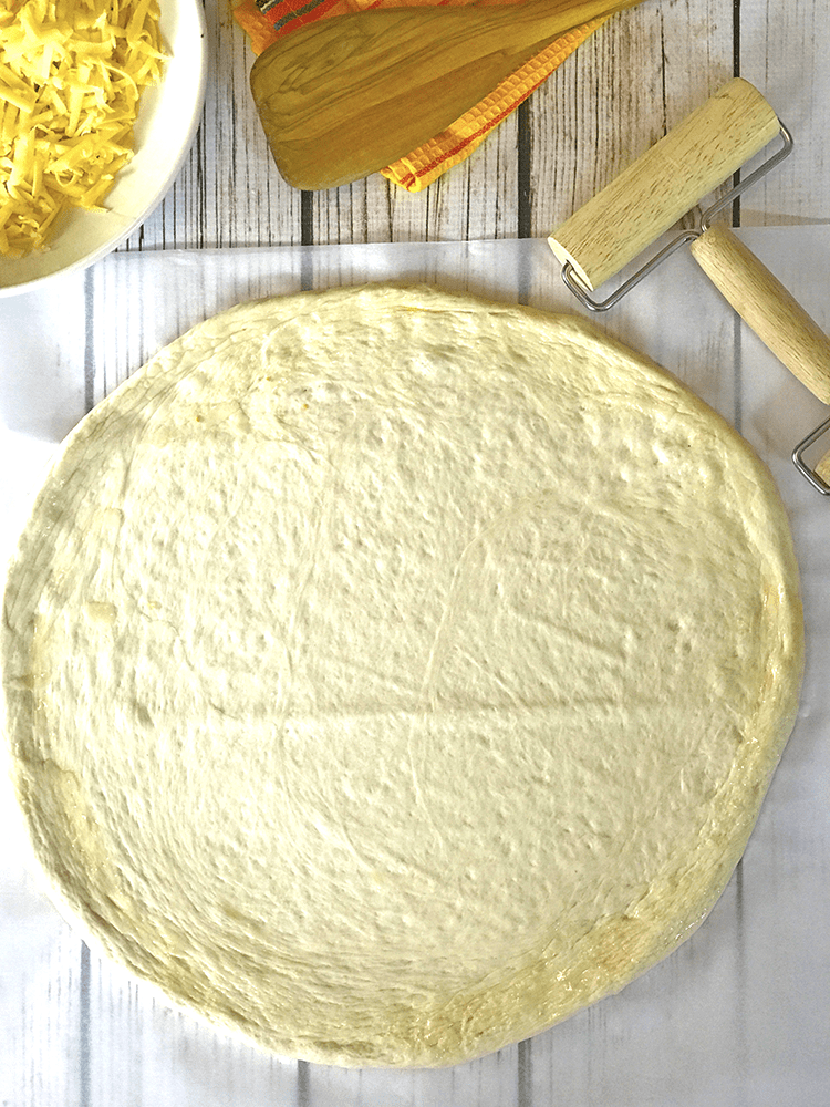 Rolled round of pizza on cloth with wooden roller