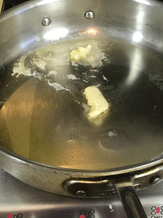 A stainless steel saute pan with oil and melting butter