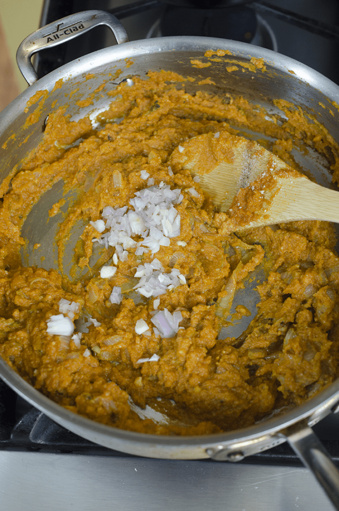 Mixed vegetables and pumpkin being stirred in saute pan with wooden spoon