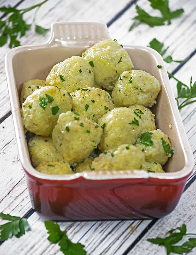serving dish of potato dumplings garnished with chopped parsley.