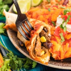 Table fork cutting into a beef enchilada