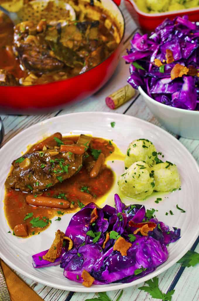 Dinner plate with braised pork and carrots, potatoe dumplings, and purple cabbage,