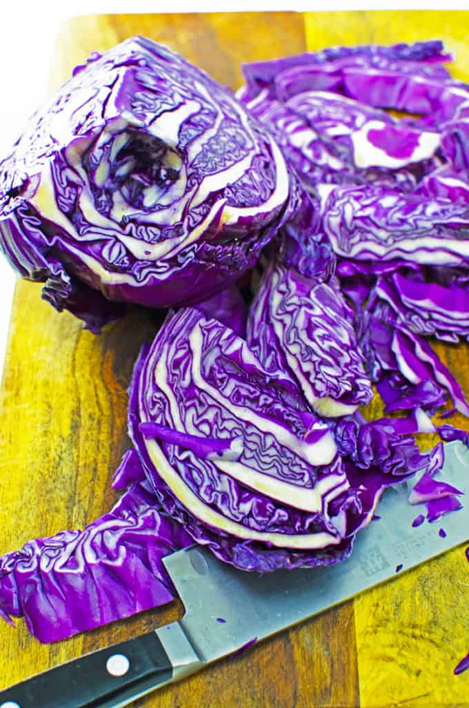 Slicesd purple cabbage on a cutting board with a chef's knife.