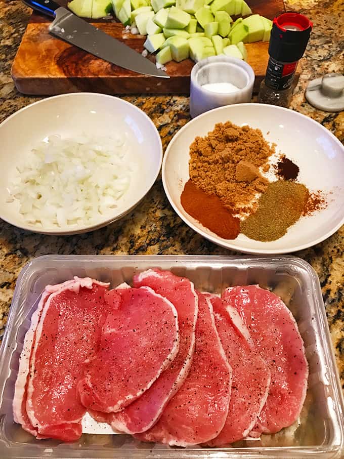 Raw pork chops, 2 dishes chopped onion and spices on counter