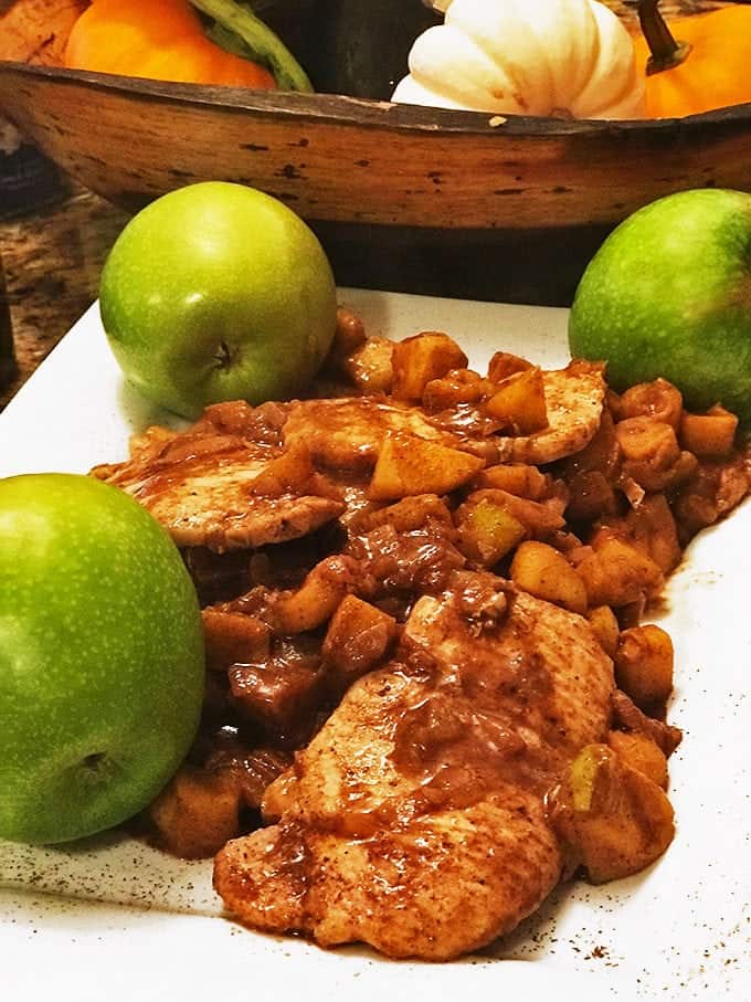 Plated pork chop in cooked vegetables with 3 green apples