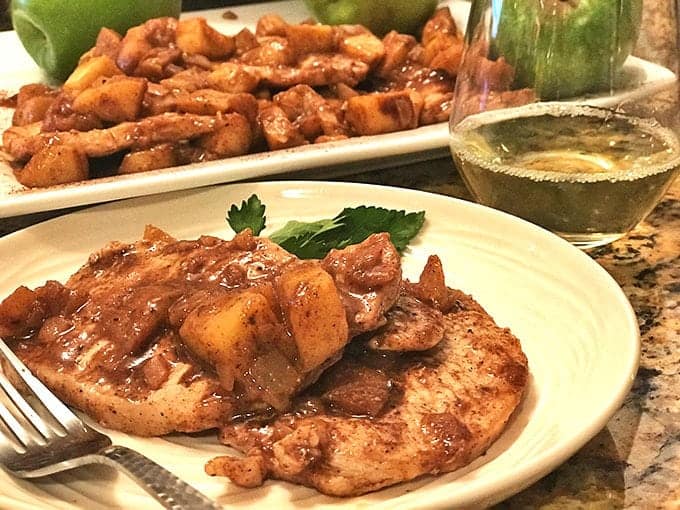 Plate of cooked meat in sauce, platter of same in background