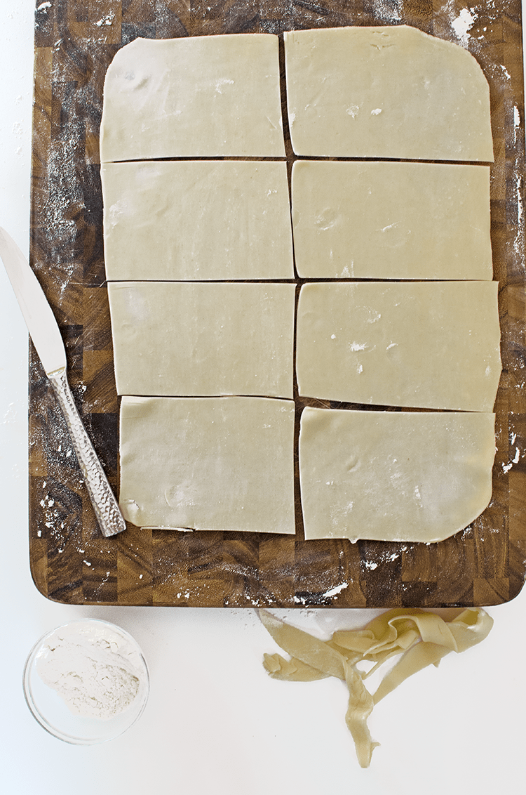 Oblong pieces dough on board with knife