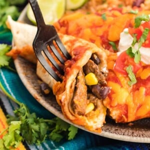 Using a fork to eat an enchilada made with leftover steak.