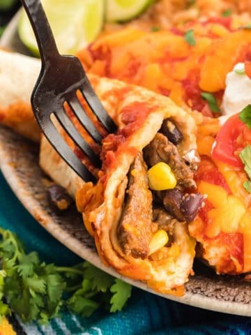 Using a fork to eat an enchilada made with leftover steak.