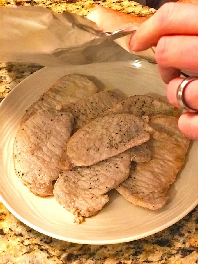 Plated cooked pork chop with someones hand