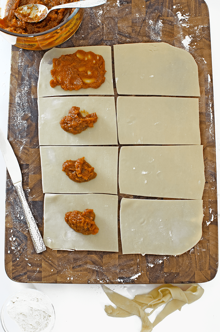 Oblong pieces dough being filled on board with knife