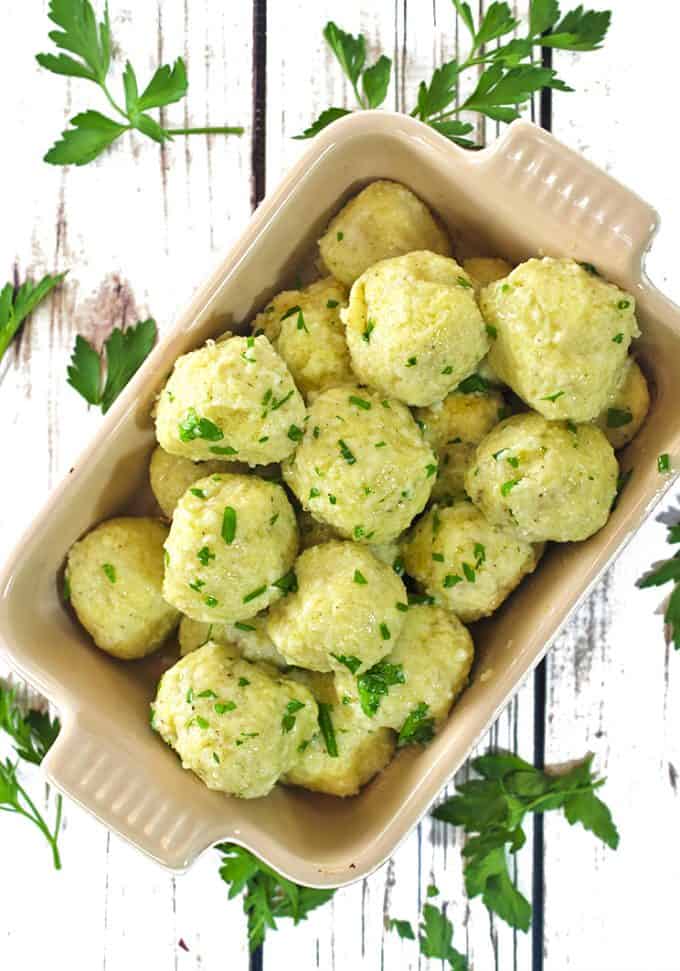 overhead view of a serving dish containing potato dumplings with Italian parsley garnish.