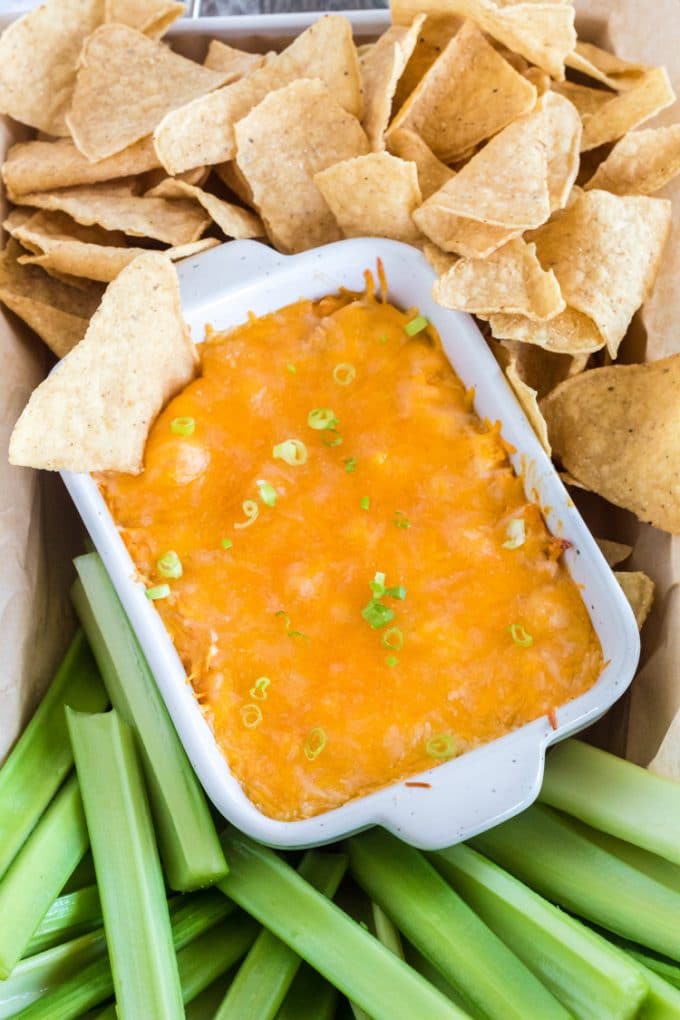 Pan of chicken wing dip with celery and nachos.