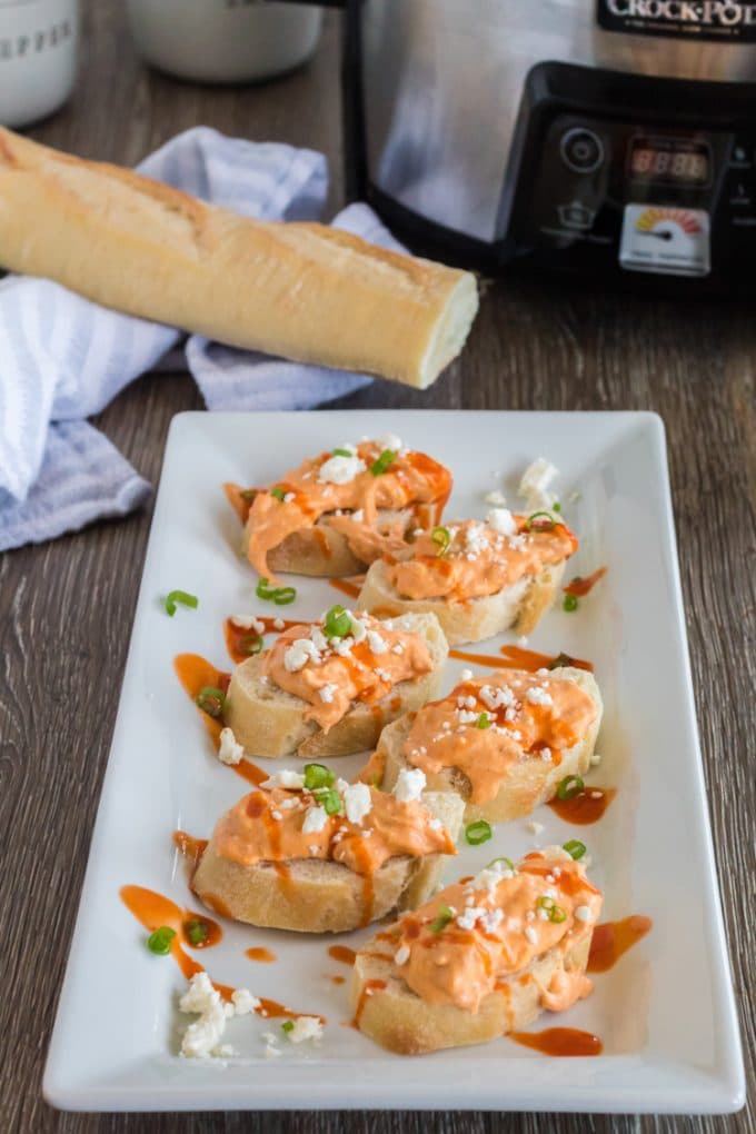 Buffalo wing dip spread over a plate of crostini.