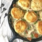 Cast iron skillet containing chicken pot pie with biscuits on top.