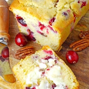 A loaf of cranberry bread sliced open on a cutting board.