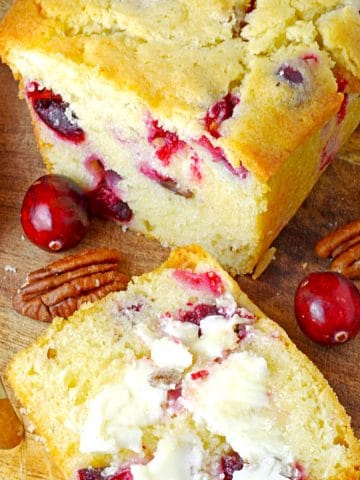 A loaf of cranberry bread sliced open on a cutting board.